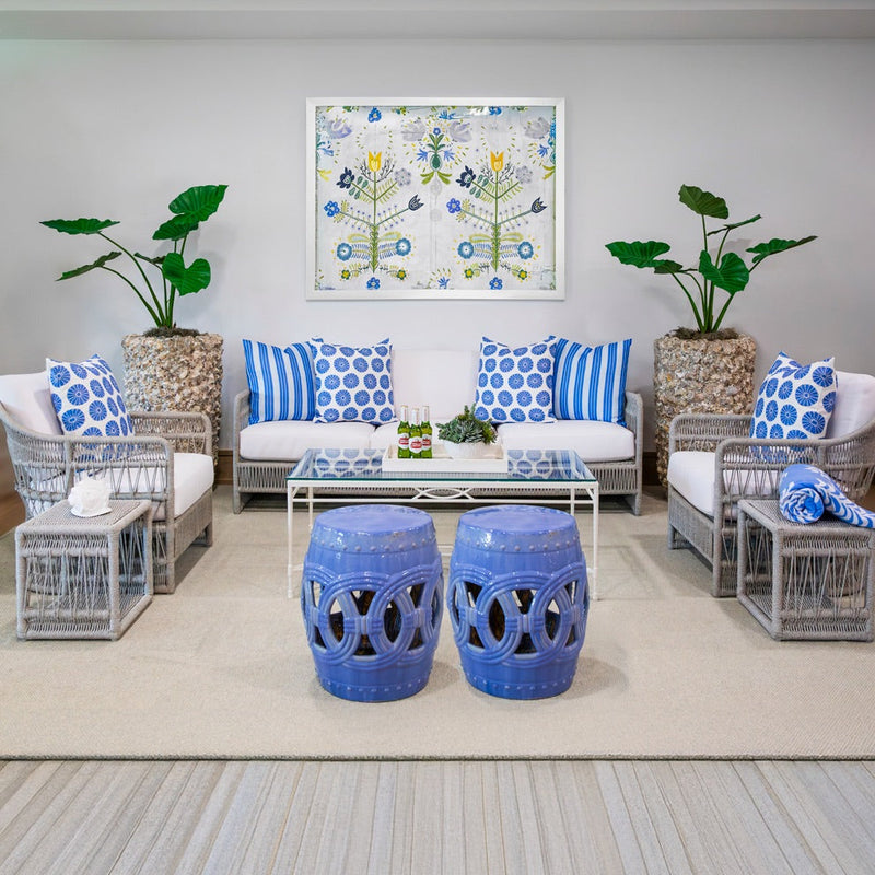 outdoor seating area with gray woven sofa and chairs and blue pillows and 2 blue garden stools