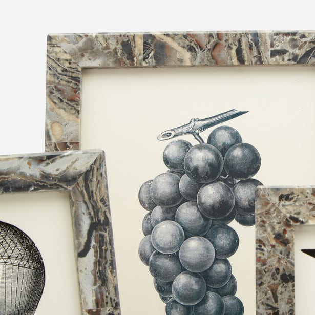 Three art prints from the Corsica Frame Collection with elegant gray marble frames are displayed; the central print highlights a detailed black and white illustration of a grape cluster.