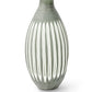 A piece from the Aster Vase Collection, this green ceramic vase boasts an elongated oval shape and vertical white grooves, accentuated by hand-etched sides.