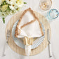 A place setting with the Kim Seybert Ruffle Napkin Ring on a plate, fork and knife, wine and water glasses, plus a bouquet of white flowers atop a woven placemat completes the elegant table decor.