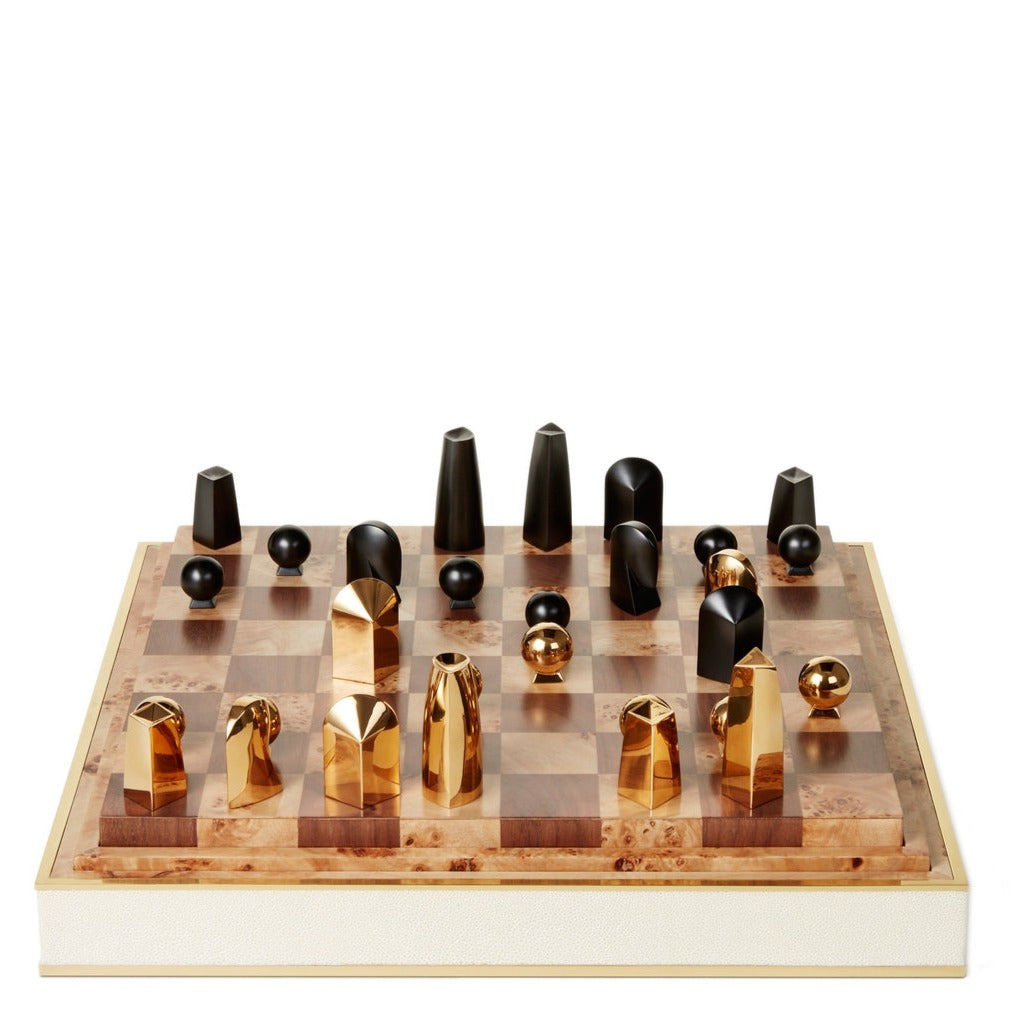 A luxurious AERIN Shagreen Chess Set featuring unique geometric gold-plated pieces on a wooden board with a cream border.