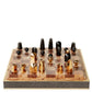 A luxurious AERIN Shagreen Chess Set with gold-plated and black pieces on a wooden board.