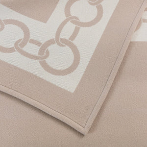 Close-up view of a folded Frette Chains Throw, Beige/Milk with a chain-link pattern along the border, perfect for an opulent throw on cold winter evenings.