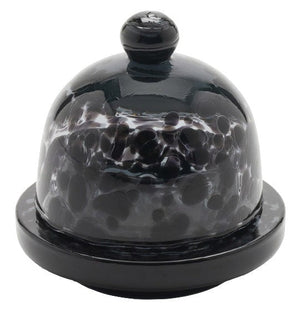 A black and white spotted glass dome cover, made from durable hand-blown glass, features a knob on top and is elegantly placed on a round base reminiscent of Blue Pheasant Andrew Butter Dish, Leopard.