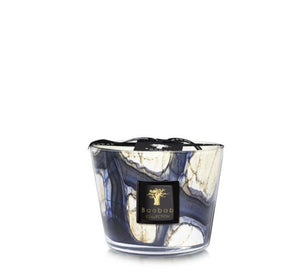 A decorative candle in a marbled blue and white glass container with a black label reading "Baobab Collection Stones Lazuli Candle," releases hints of cardamom, adding a touch of exotic spice to its elegant presentation.