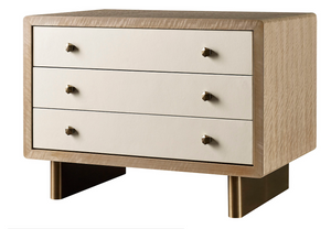 A Waterfall Nightstand with a natural wood frame, three white drawers, and brass handles, supported by brass legs.