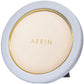 A round, white compact adorned with sophisticated gold detailing and the brand name "AERIN" elegantly inscribed in gold on the lid from the AERIN Classic Piero Leather Frame Collection.