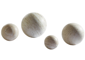 Four beige marble orbs of varying sizes, crafted as hand-honed Travertine Spheres, are arranged in a diagonal line on a white background.