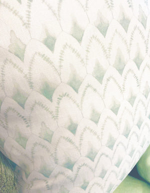 A close-up of the Arrowhead Rainwashed Pillow showcases its repeating scalloped pattern in light green and white, crafted with premium materials and careful attention to detail.