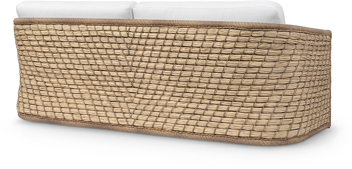 The Capitola Sofa features a woven rattan frame made from synthetic seagrass and white seat cushions, shown from the back on a white background.
