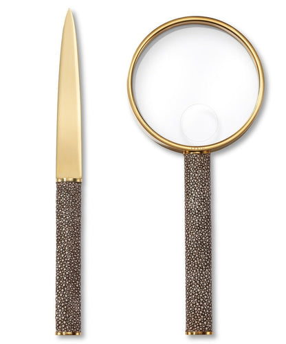 An AERIN Shagreen Magnifying Glass and Letter Opener with gold-colored accents and textured brown handles are placed side by side on a white background. This elegant set makes the perfect home office gift.