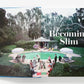 Open book displaying a poolside scene with several people gathered around a pool, reminiscent of Slim Aarons photography, and the text "Slim Aarons: The Essential Collection" on the right-hand page.