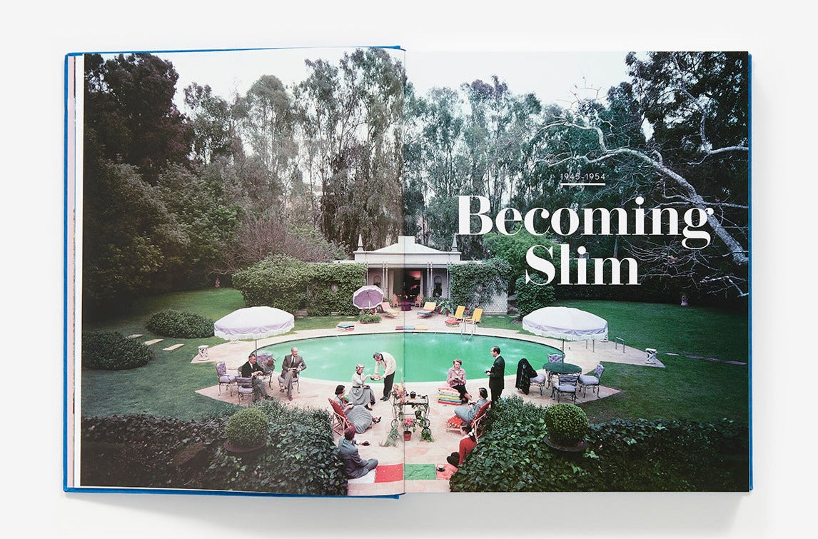 Open book displaying a poolside scene with several people gathered around a pool, reminiscent of Slim Aarons photography, and the text "Slim Aarons: The Essential Collection" on the right-hand page.