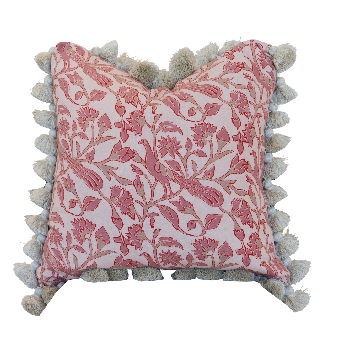 The Peacock Garden Pillow is a square decorative pillow showcasing a pink floral pattern and beige tassels along the edges, featuring a hidden zipper closure for a seamless look, displayed against a white background.