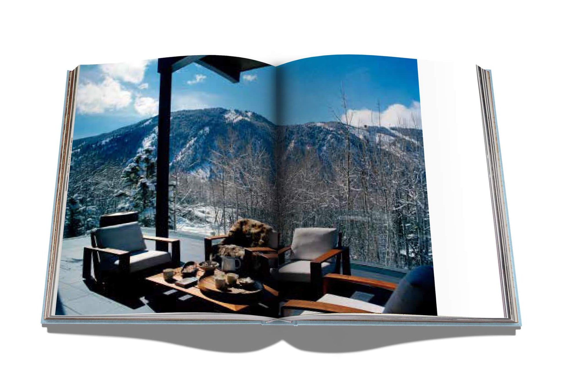 A rustic-chic Assouline book with a view of mountains and a chair, inspired by Aspen Style.