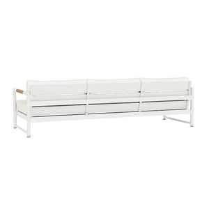 The Breeze XL 3 Seat Sofa has a white finish with a metal frame, three seat and back cushions, and teak accent armrests on each side, creating a stylish modern look when viewed from the back.