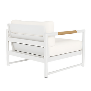The Breeze XL Lounge Chair in White Panama Blanco features a white metal frame, teak-accented armrests, and off-white cushions, shown from a rear side angle.