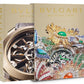 Two volumes of "Bulgari Beyond Time" feature a close-up of Bulgari watches and a colorful jeweled piece on the covers, capturing the essence of Swiss-Italian watchmaking and high-jewelry collections.
