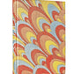 A hardcover book with a vibrant cover featuring a marbled pattern of red, yellow, blue, and beige swirls rests elegantly beside a luxurious caftan. The title "Caftans: From Classical to Camp" is visible on the spine, inviting readers to dive into its Resort-inspired tales.