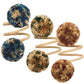 The Kim Seybert Casbah Napkin Ring features three coiled beige stems, each topped with a multicolored yarn pom-pom in blue, green, brown, and tan, adding organic elegance to your table setting.