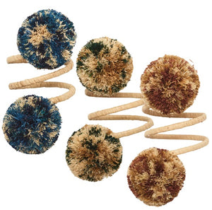The Kim Seybert Casbah Napkin Ring features three coiled beige stems, each topped with a multicolored yarn pom-pom in blue, green, brown, and tan, adding organic elegance to your table setting.