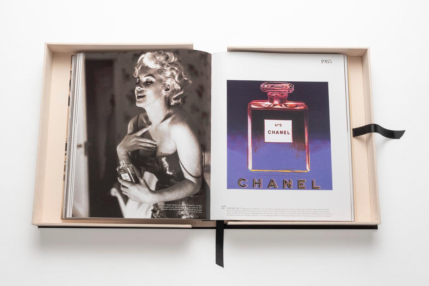 Open book featuring a black-and-white photo of a woman holding a bottle on the left page and an advertisement for *The Impossible Collection: Chanel* on the right page, embodying timeless luxury fashion.