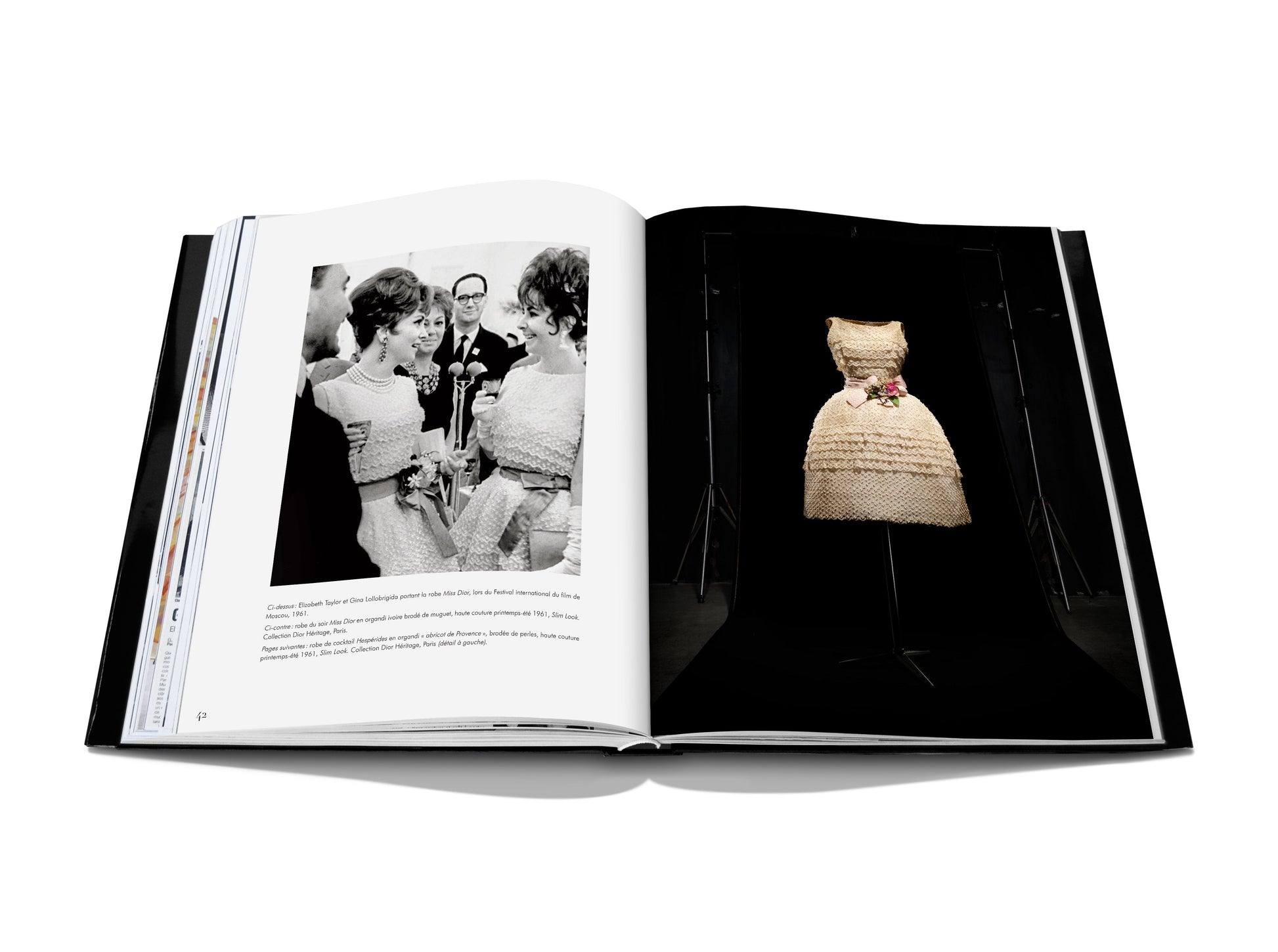 An open book displaying original photography by Laziz Hamani features a black-and-white photograph of two women talking on the left page and a Dior: Marc Bohan haute couture creation with a floral decoration on the right page.