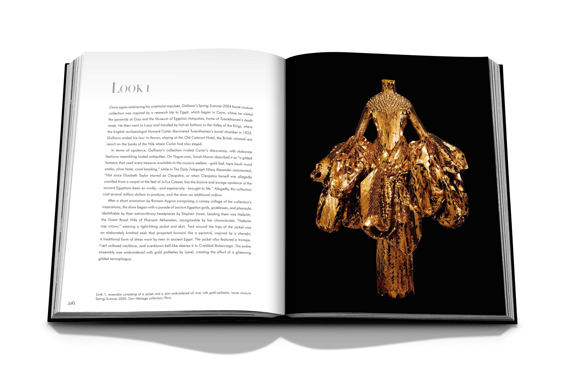 An open book displaying an image of an elaborate, gold-colored garment on the right page and descriptive text on the left page with the heading "LOOK 1: A breathtaking masterpiece by John Galliano for Dior: John Galliano, epitomizing haute couture.