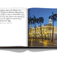 A hardcover book open to a page displaying a photograph of a lit-up, ornate building at night surrounded by palm trees, with text on the left page describing the unique charm of Havana Blues and its role in the Cuban revolution.