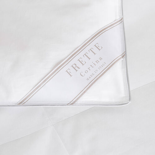 Close-up of a white Frette Cortina Duvet Insert, Light Density, crafted from luxurious 380 thread count cotton sateen, with a label indicating it is made in Italy.