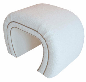 A white, semi-circular, arch-shaped pillow with textured fabric and a seam outlining the curved edges, reminiscent of an O'Neal Small Bench with custom upholstery.