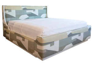 The Gustav Bed, King features a white mattress and an abstract camouflage-patterned fabric with wood details, complemented by an upholstered headboard and frame.