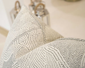 Close-up of a Maralinga Ombre Pillow with intricate dot designs, crafted from the finest materials. Two metallic lanterns with wooden handles are slightly out of focus in the background.