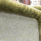 Close-up of a Deco Rolled Arm Chair back upholstered in fabric with a green and white scallop pattern, reminiscent of Kips Bay Show House design, bordered by velvet-like green fabric.