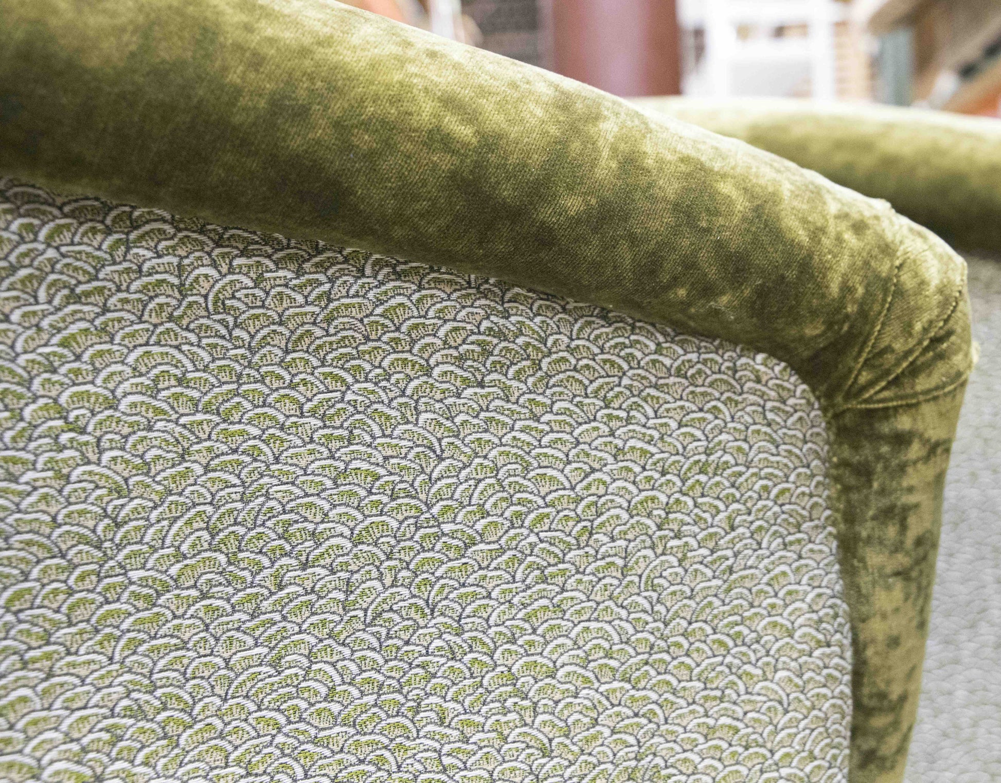 Close-up of a Deco Rolled Arm Chair back upholstered in fabric with a green and white scallop pattern, reminiscent of Kips Bay Show House design, bordered by velvet-like green fabric.