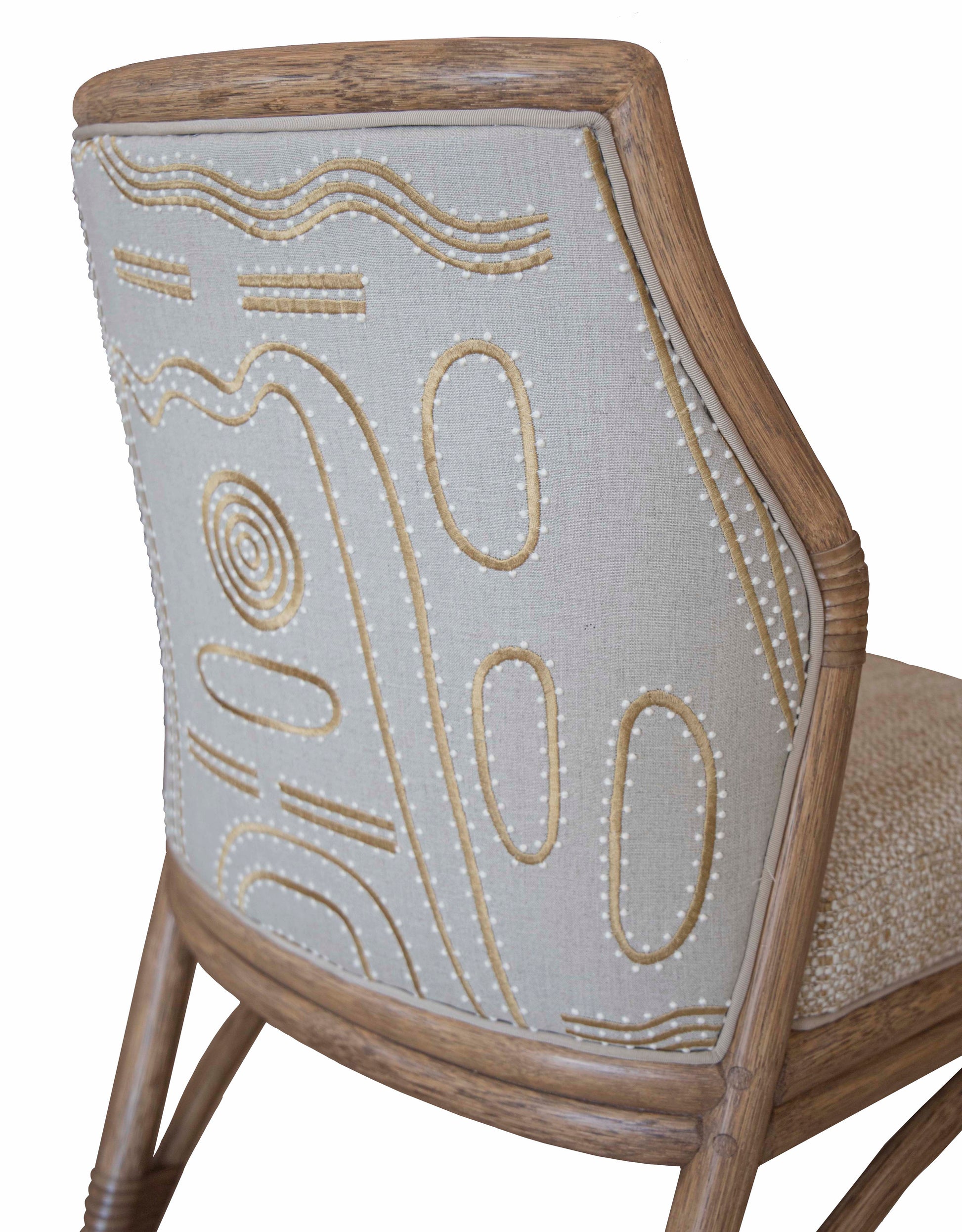 Close-up of the Lantana Side Chair, a wooden chair with beige fabric upholstery, featuring abstract embroidered patterns in white and light brown threads on the backrest. This piece showcases McGuire craftsmanship and a flexible modern design.