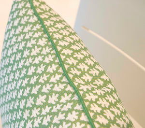 Close-up of the Burma Meadow Outdoor Pillow—green with a white leaf pattern and green piping—crafted from premium materials, shown against a light grey background.