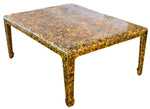 The Gerrit Cocktail Table features a square design with a yellow and black speckled surface, accented by sleek metal inlays on its four straight legs.