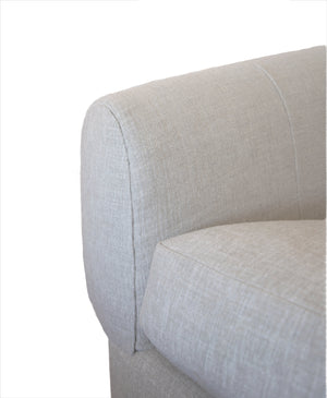 Close-up view of the arm and cushion of the light gray fabric Obi Sofa against a white background, capturing its modernist design and evoking a sense of relaxation.