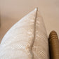 Close-up of a Deco Stripe Mushroom Lumbar Pillow, crafted from the finest materials, resting on a wicker chair.