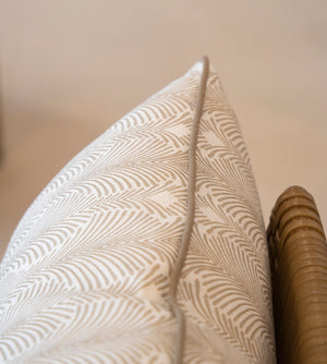 Close-up of a Deco Stripe Mushroom Lumbar Pillow, crafted from the finest materials, resting on a wicker chair.