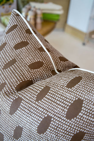 Close-up of the Abacus Walnut Reverse Pillow, a brown decorative pillow with white dotted and oval patterns and white piping along the edge—highlighting custom-made quality.