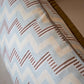 Close-up of the Ziggy Sky Lumbar Pillow, featuring a blue, white, and brown zigzag pattern on a light fabric—perfect for enhancing your pillow collection with style.