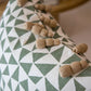 Close-up of our Circus Pillow, custom-made with a green and white geometric pattern and beige tassels, crafted from the finest materials.