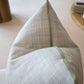 A close-up of the Helios Olive Pillow, a gray and white textured custom-made pillow with a green zipper, crafted from premium materials and displayed on a light-colored surface indoors.