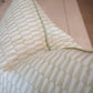 Close-up of the Tane Light Dusk Pillow, featuring a beige and light green checkered design with green piping, set against a neutral background.