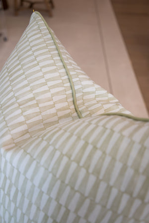 Close-up of the Tane Light Dusk Pillow, featuring a beige and light green checkered design with green piping, set against a neutral background.