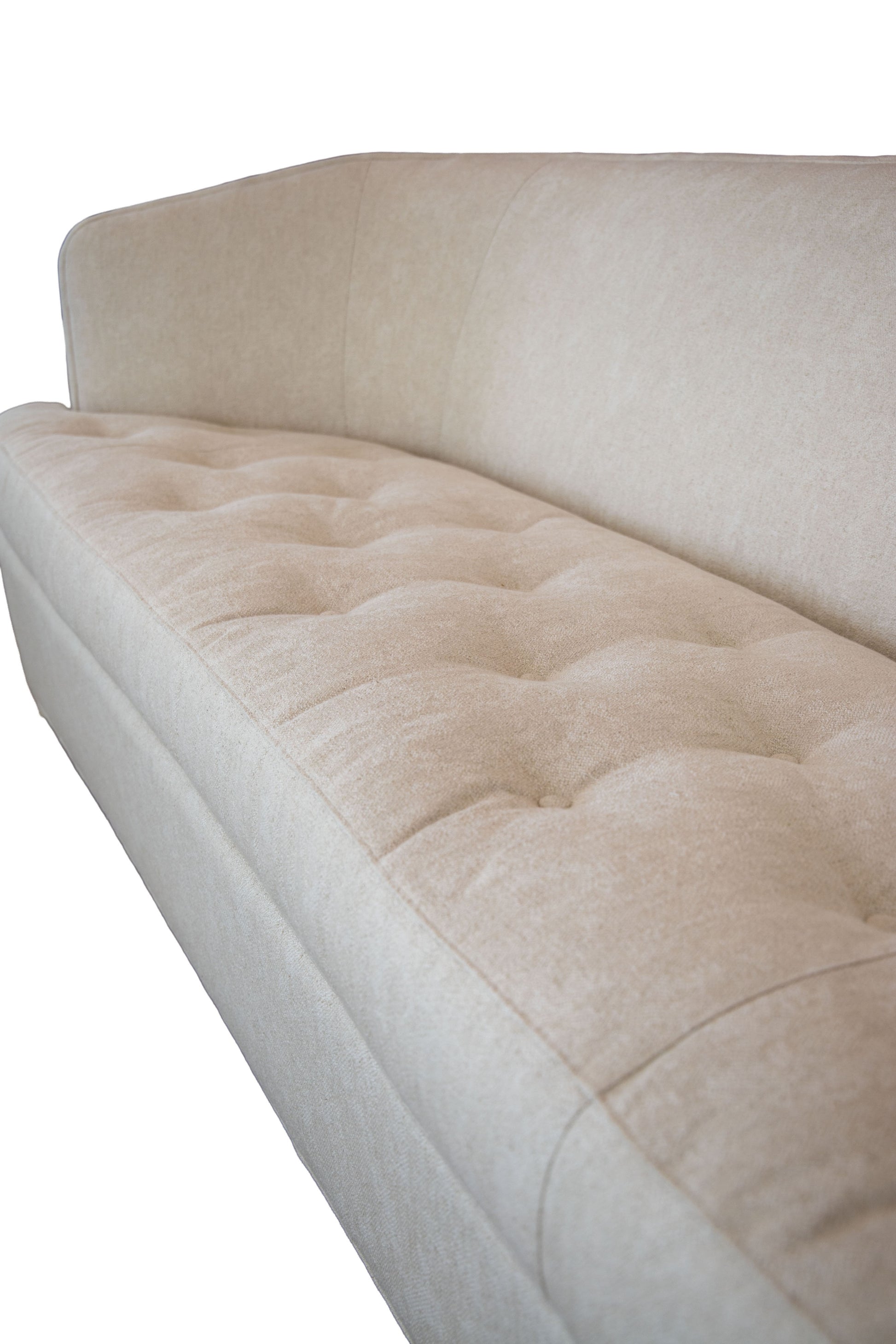 Close-up of the Aldo Sofa, showcasing its beige upholstery with tufted seat cushions and a straight backrest. This timeless design brings sophistication, elegantly highlighted against a white background.
