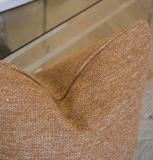 Close-up of the Georgia Cloth Pillow, featuring a rich textured brown fabric, custom-crafted with premium materials, displayed in front of a glass table on a light wood floor.