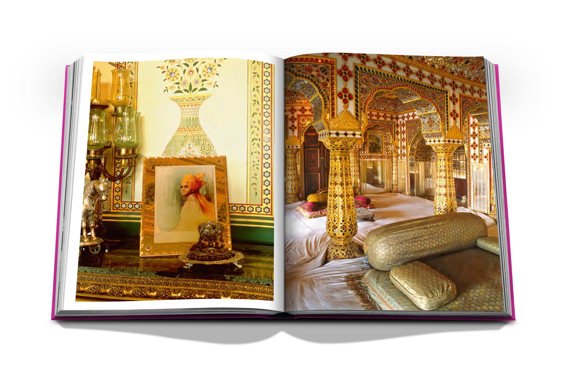 An open book reveals the ornate interior designs of a luxurious room resembling the Jaipur Splendor, complete with detailed artwork, stately columns, and plush cushions.